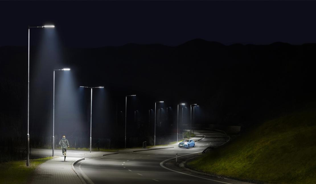 Piéton et voiture éclairées de nuit par des luminaires intelligents