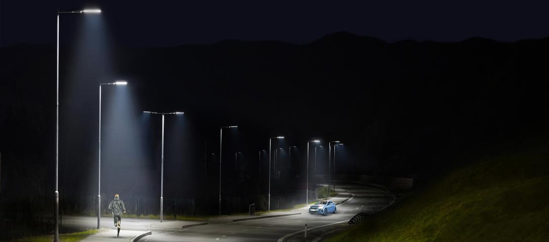 Piéton et voiture éclairées de nuit par des luminaires intelligents